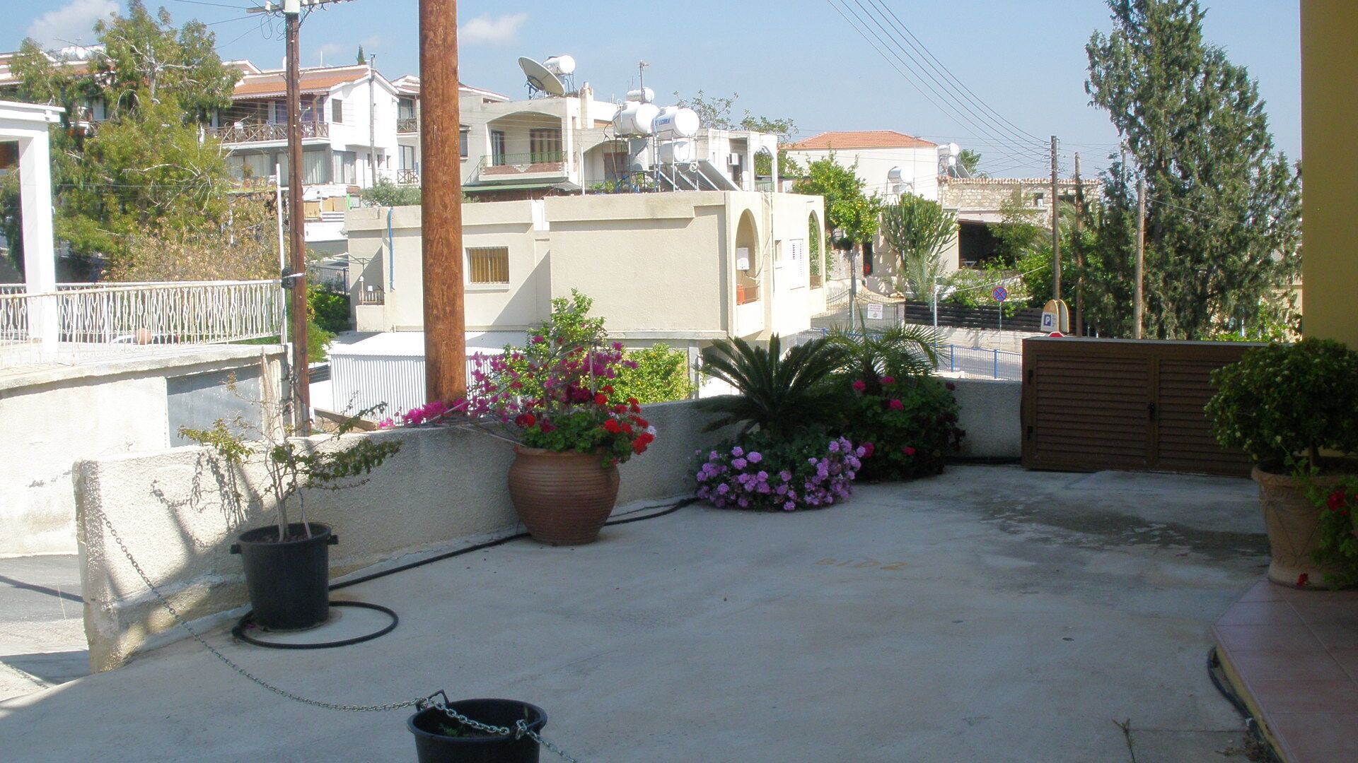 A rooftop terrace with potted plants, a water tank, and a gated entrance.