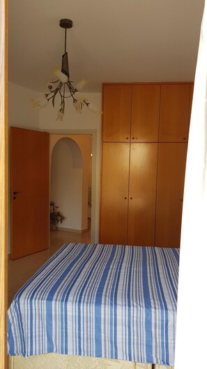 Un dormitorio con cama, armario y una araña.