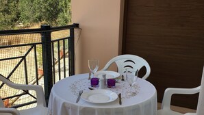 A round table with a floral tablecloth, white chairs, and a sun decoration on the wall. - Private development of 12 Apartments in center of Peyia. Near to Coral Bay. (Peyia)