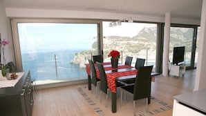 Un espace repas moderne avec une grande table, des chaises et une vue sur la mer.