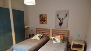A bedroom with two single beds, a wooden headboard, a nightstand, a lamp, and a deer head mounted on the wall. - Bouganville Residence - Elite apartment with swimming pool, sports field and games. (Calatabiano)