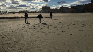 Une plage de sable avec des empreintes et quelques personnes.