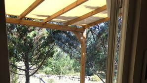 Une terrasse en bois avec un hamac sous une pergola.