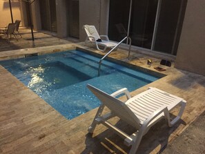 Una piscina amb dues gandules blanques i una escala metàl·lica.