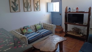 Ein Wohnzimmer mit einer Couch, einem Couchtisch und einem Fernseher auf einem Holzständer.