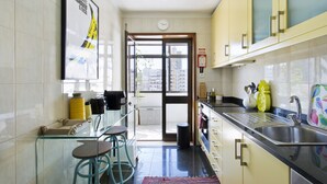 Una cocina moderna con un ventanal grande, un lavamanos y taburetes de bar.