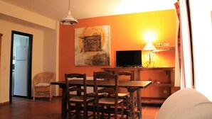 A dining area with a table and chairs, a television, and a painting on the wall. - Rural apartment Aptos. Rural Tourism Las Maravillas for 5 people (Jaén)