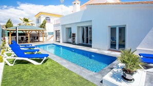 Una piscina amb gandules blaves, una zona de seients coberta i una planta en test.