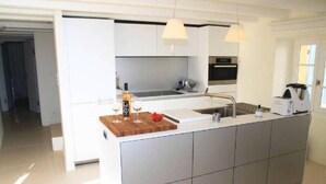 A modern kitchen with a central island, white cabinetry, and pendant lighting. - L'île-Rousse with its feet in the water (L'Île-Rousse)