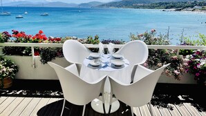 A table and chairs on a balcony overlooking a coastal view with boats and mountains. - L'île-Rousse with its feet in the water (L'Île-Rousse)