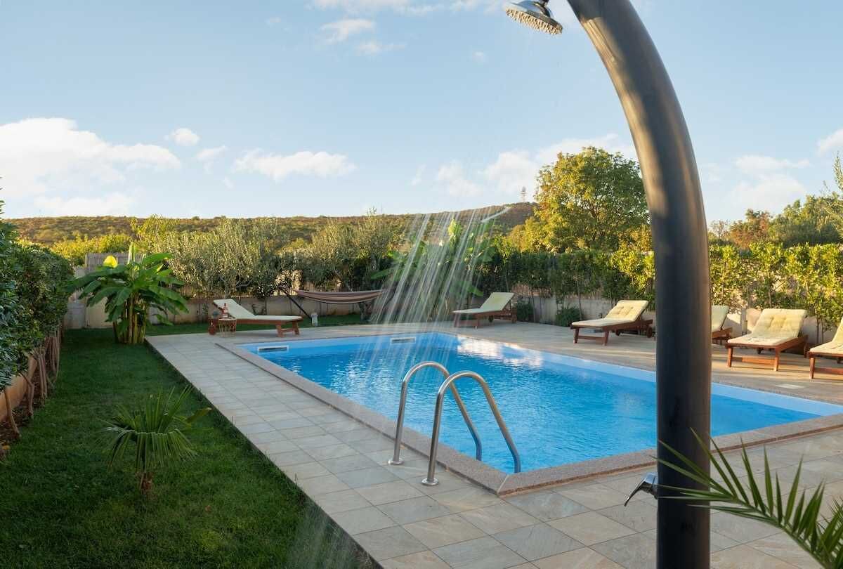 A swimming pool with a water feature, surrounded by a grassy area and lounge chairs.
