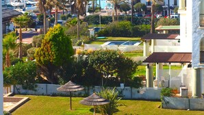 Une vue sur la côte, avec un port de plaisance, des palmiers et un bâtiment blanc doté de balcons.