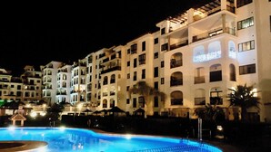 Un hôtel doté de nombreux balcons, d’une piscine et d’une façade bien éclairée.