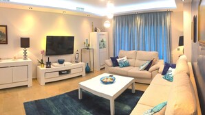 Un salon moderne comprenant un canapé, une table basse, un téléviseur et des objets de décoration.