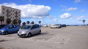 A parking lot with several cars, a building with balconies, and a clear sky.