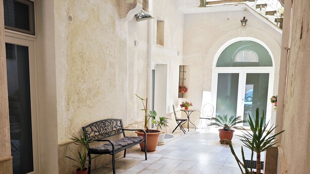A spacious courtyard with a bench, potted plants, and a tiled floor.