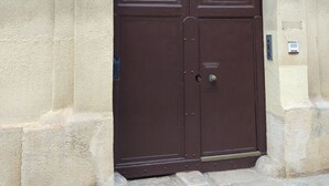 A large, dark brown double door with a keypad lock, set within a stone archway.