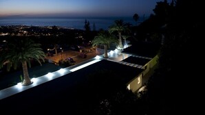 A coastal property at dusk with a view of the ocean, palm trees, and a lit pathway. - Wonderful Casa El Balcon Grande in La Orotava (La Orotava)