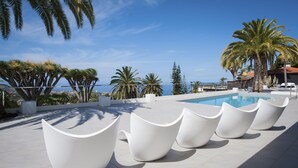A poolside area with modern white chairs and palm trees. - Wonderful Casa El Balcon Grande in La Orotava (La Orotava)