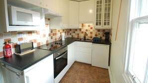 A compact kitchen with white cabinets, a microwave, a toaster, and a sink. - Elegant first floor apartment for 2 people, with great views of mountains.  (Taynuilt)