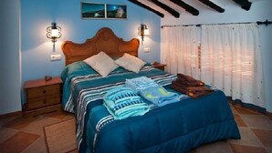 Ein Schlafzimmer mit einem hölzernen Bett, zwei Wandlampen, einem Bild von einem Nachthimmel und einem Fenster mit weißen Vorhängen.