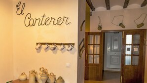 Ein Flur mit einem an der Wand befestigten Schild mit der Aufschrift 'El Carterer', einem Regal mit Keramiktassen und einer Tür, auf der 'SALIDA' steht.