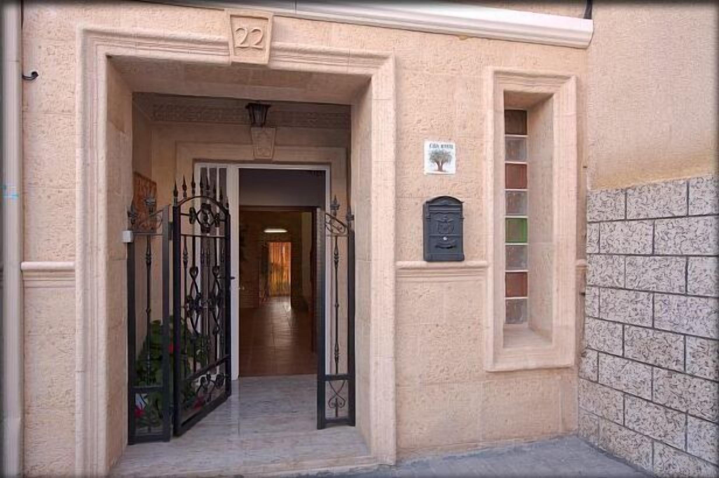 A building entrance with a number '22' above the door, a metal gate, and a mailbox on the wall.