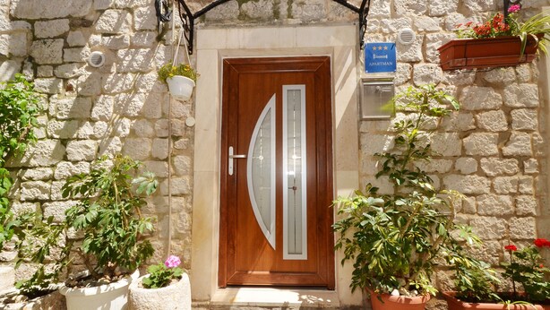 A stone building with a wooden door, potted plants, and a sign indicating an apartment. - Apartment Nikolina house in center of the old town Trogir (Trogir)