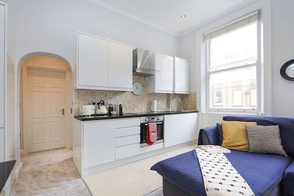 A modern kitchen with white cabinets, a built-in oven, and a window providing natural light.