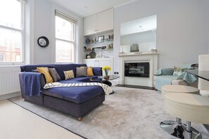 A modern living room with a sofa, a fireplace, and a dining area.