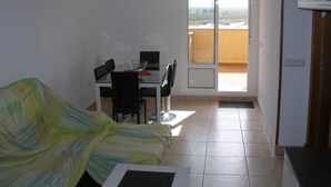 A room with a bed, a dining table with chairs, a chandelier, and a sliding glass door leading to a balcony. - Magnificent Penthouse in Barbate (Barbate)