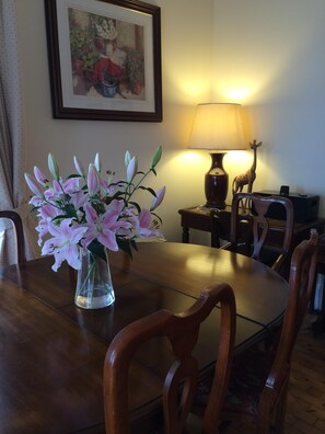 A dining table with a vase of pink lilies, a lamp, and a giraffe figurine.