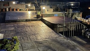 Una terraza en la azotea con suelo de piedra, mobiliario exterior y vista al océano.
