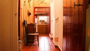 Un pasillo estrecho con paredes y puerta de madera, y suelo de baldosas.