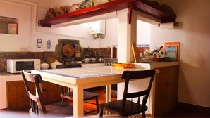 Cocina compacta con mesa, sillas, microondas y diversos utensilios de cocina.