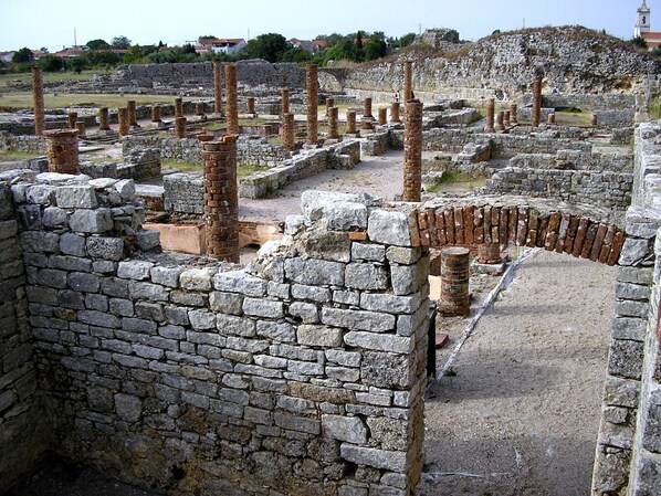 Ruinas antiguas con muros y columnas de piedra.