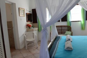 A bedroom with a bed, a chair, a vanity, and a window with curtains. - Beach House with private Pool and use of Tennis Court. Breathtaking Views. (Vipingo, Nr Kilifi, Vipin)