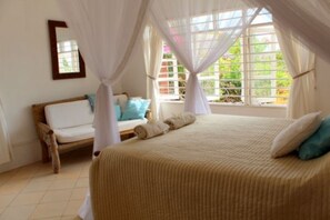 A bedroom with a bed, a bench, and a window with curtains. - Beach House with private Pool and use of Tennis Court. Breathtaking Views. (Vipingo, Nr Kilifi, Vipin)