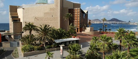 A coastal building with a dome, palm trees, and a view of the sea.