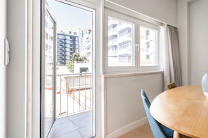 Um apartamento moderno com varanda, área de jantar com mesa redonda e amplas janelas com vista para a paisagem urbana.