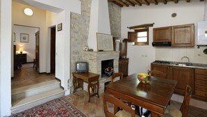 Una cocina rústica con chimenea de piedra, armarios de madera y un comedor con mesa y sillas.