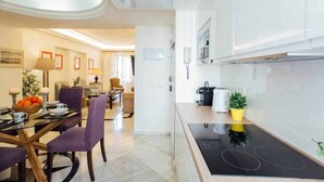 Eine moderne Küche mit Einbauherd, ein Essbereich mit Tisch und Stühlen sowie ein Wohnzimmer mit Sofa und Couchtisch.