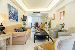 A living room with a sofa, armchairs, a coffee table, and a TV.