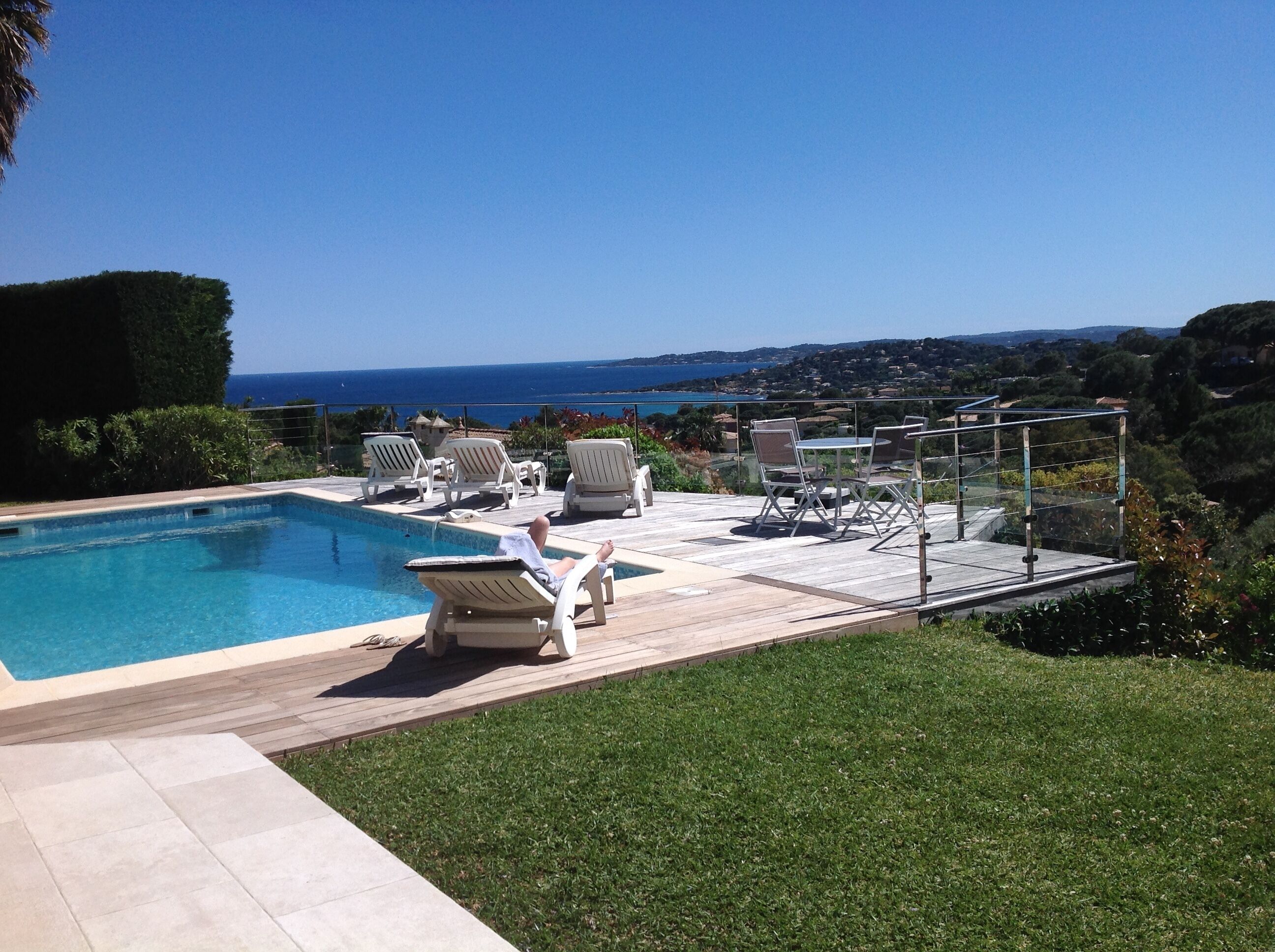 A pool area with lounge chairs and a view of the sea.