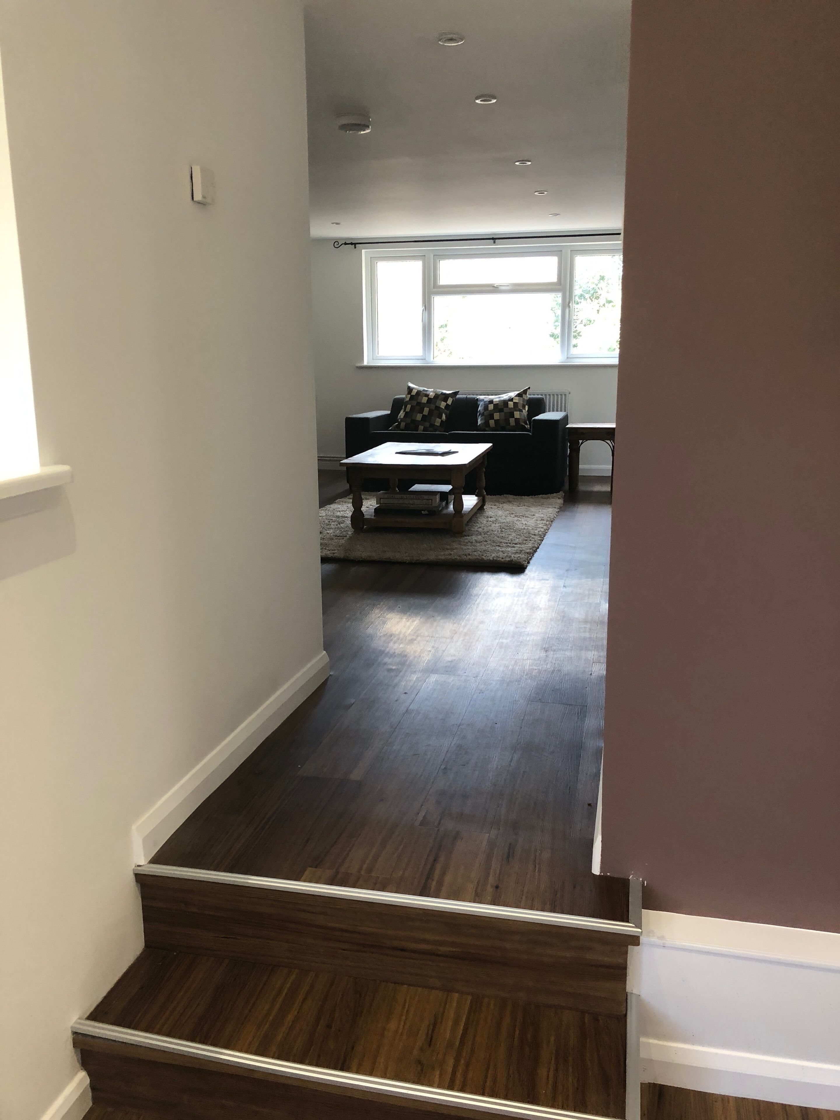 A staircase leading to a living room with a dark wood floor, a sofa, and a coffee table.