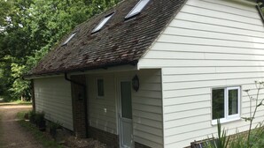 A single-story house with a sloped roof, a front door, and a small window. - Rural Retreat in deepest Sussex (Lewes)