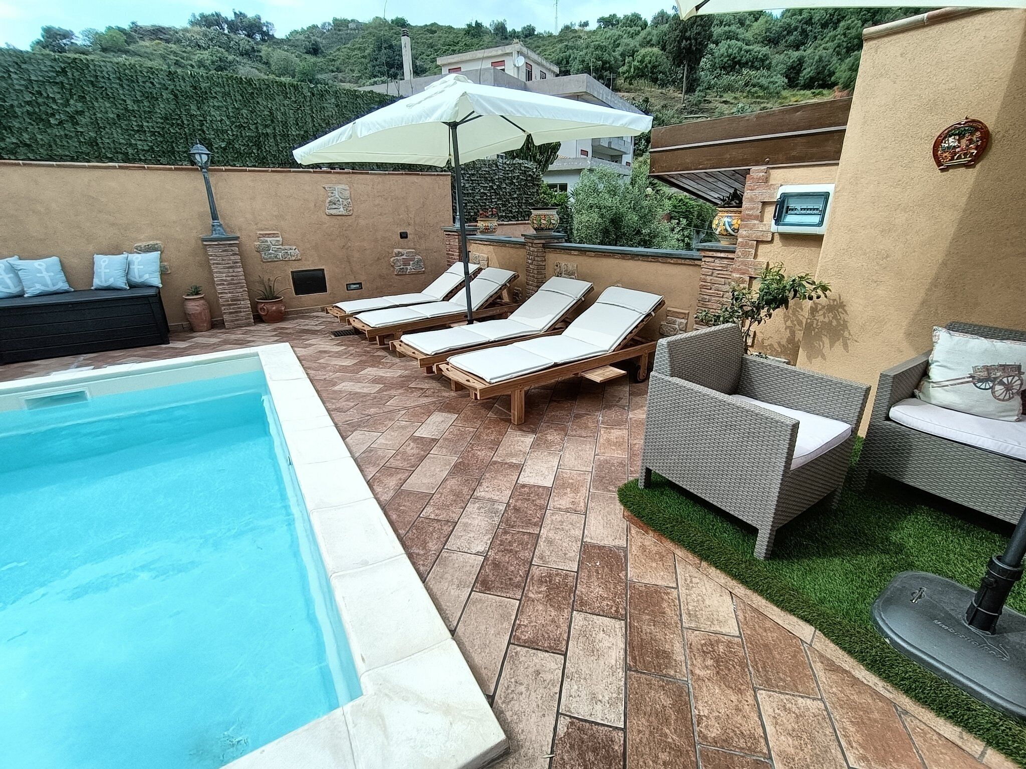 Un área de piscina con sillas de descanso y un espacio de estar techado.