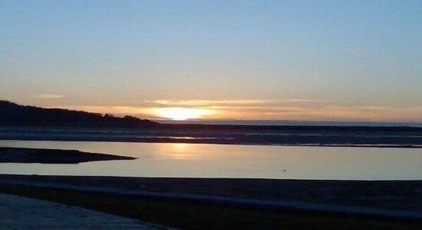 A sunset over a calm body of water with a distant shoreline.