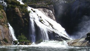Ett stort vattenfall som störtar nerför en brant klippa och ut i en flod.