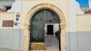A historic building entrance with a large arched door, a decorative white facade, and a sign indicating a rural guesthouse. - Self catering Puerta del Agua for 6 people (Uclés)